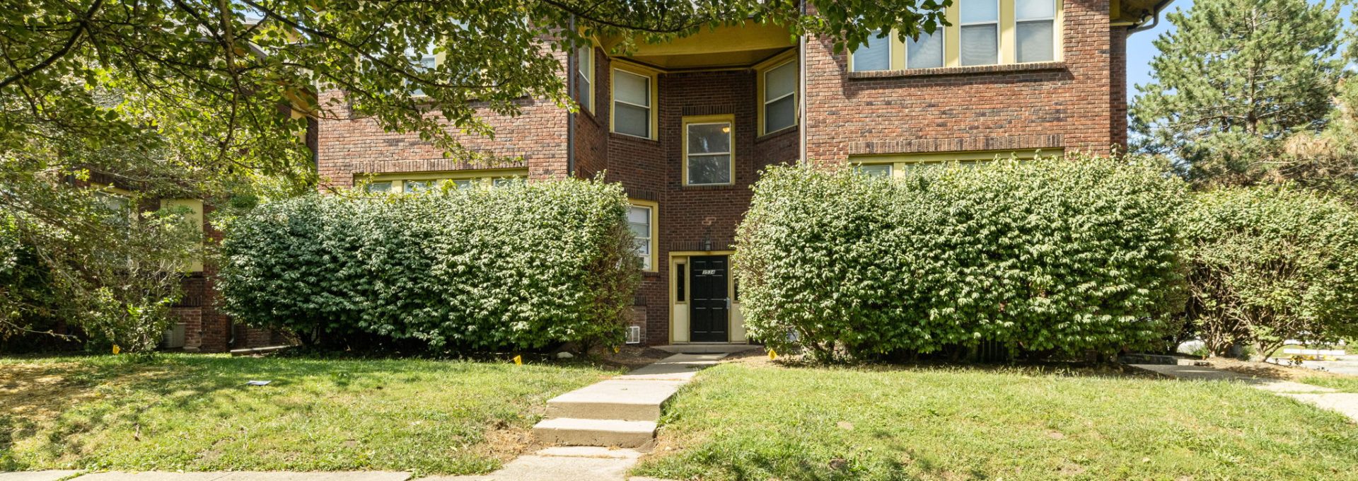 a brick home with trees and bushes in front at The Villages at Fall Creek